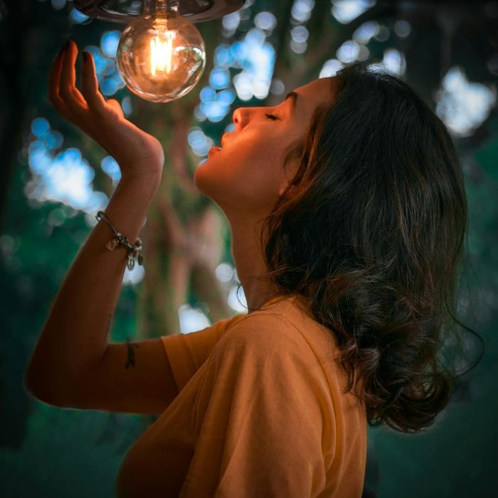 Woman in a calming stretch pose illuminated by warm light